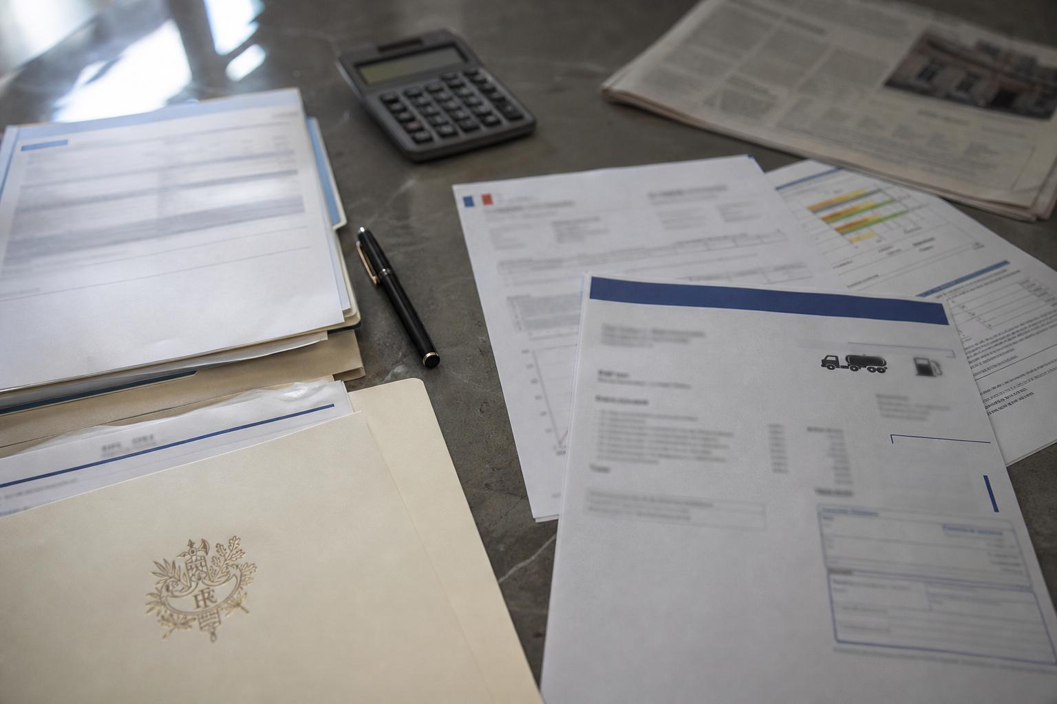 Vue zénithale d’un bureau administratif français avec documents budgétaires, calculatrice et dossier officiel, illustrant l’aide carburant et la pression sur les finances publiques.