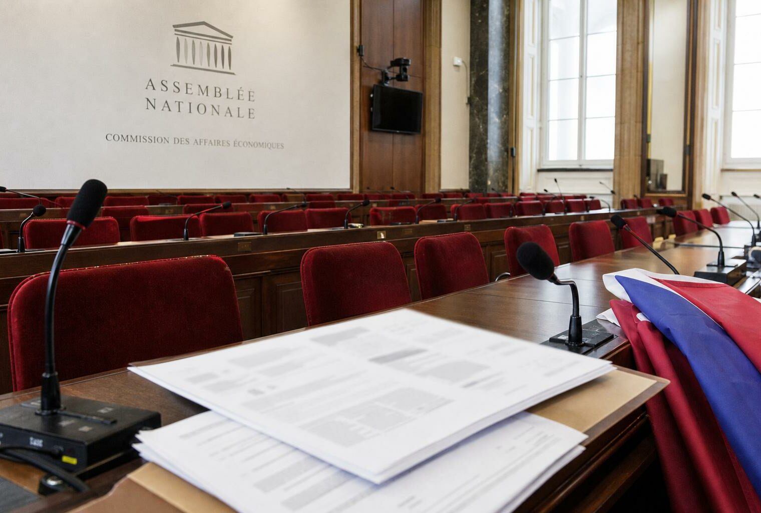 Salle de commission de l’Assemblée nationale avec sièges rouges, micros et amendements flous sur la loi agricole.