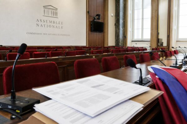 Salle de commission de l’Assemblée nationale avec sièges rouges, micros et amendements flous sur la loi agricole.