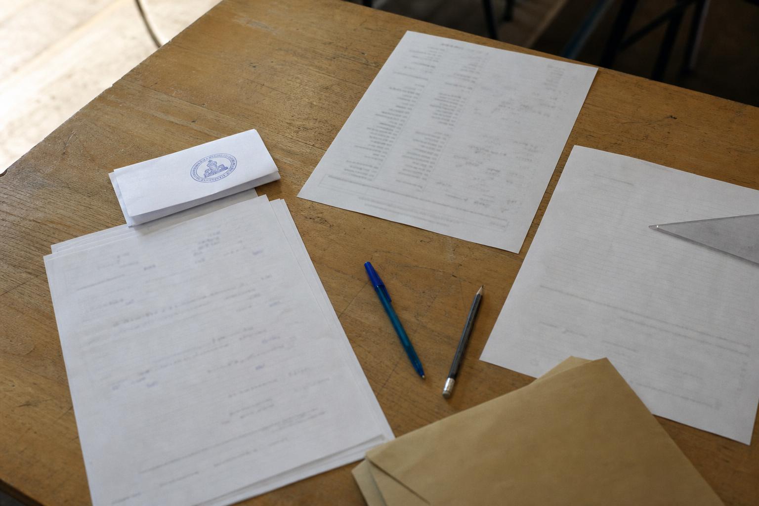 Vue de dessus d’une copie d’examen et de documents officiels français sur un bureau d’école, ambiance documentaire neutre.
