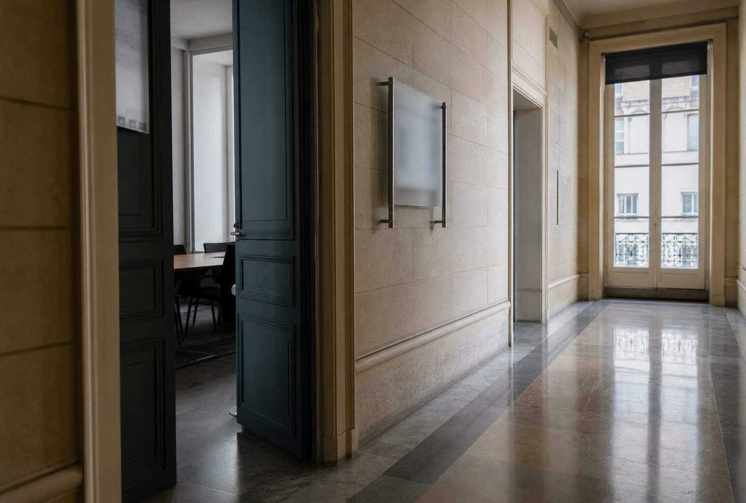 Couloir clair d’institution française avec porte sobre et salle d’audition visible au fond.