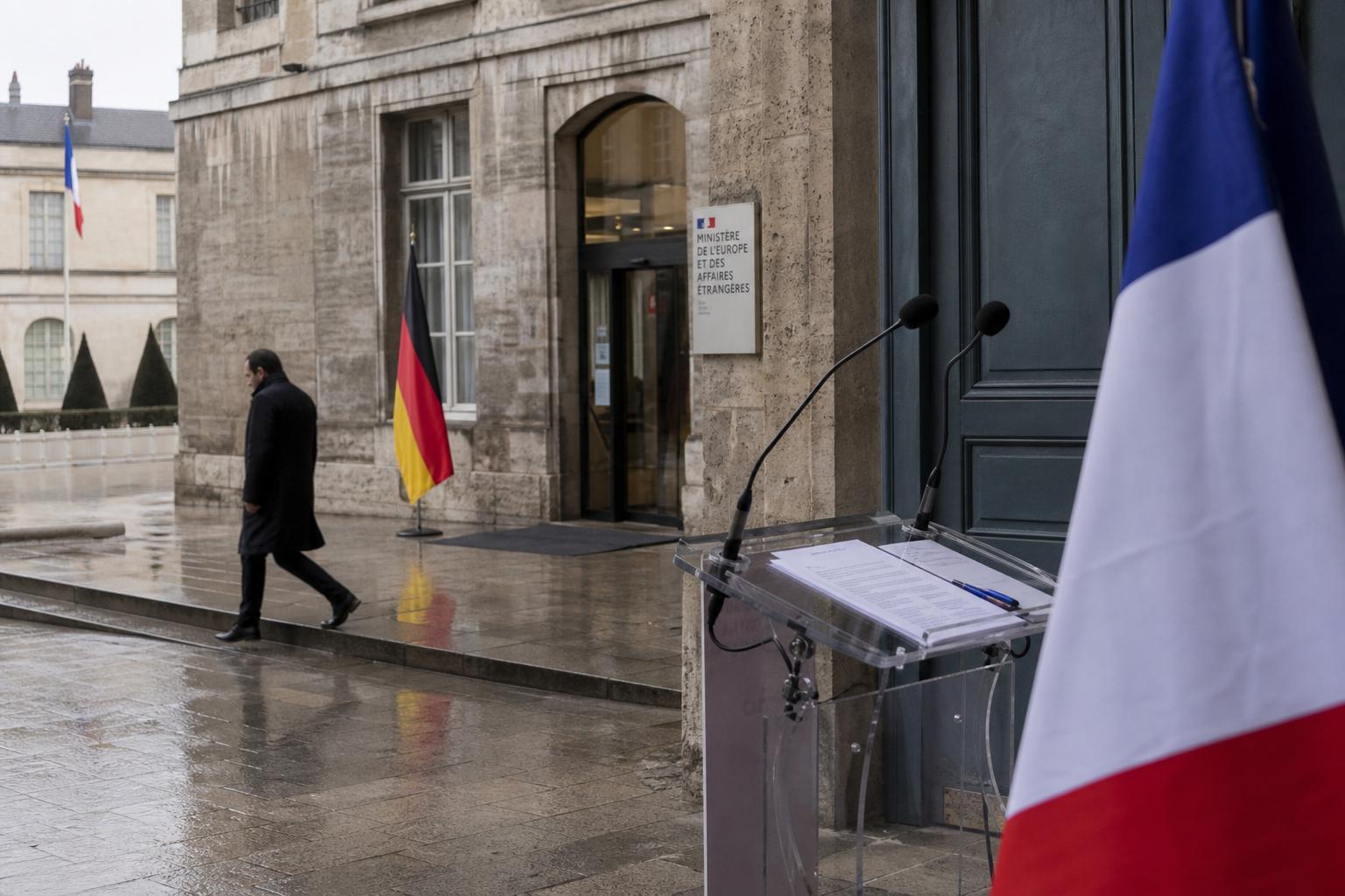 Scène diplomatique à Paris avec drapeaux français et allemand devant un bâtiment institutionnel