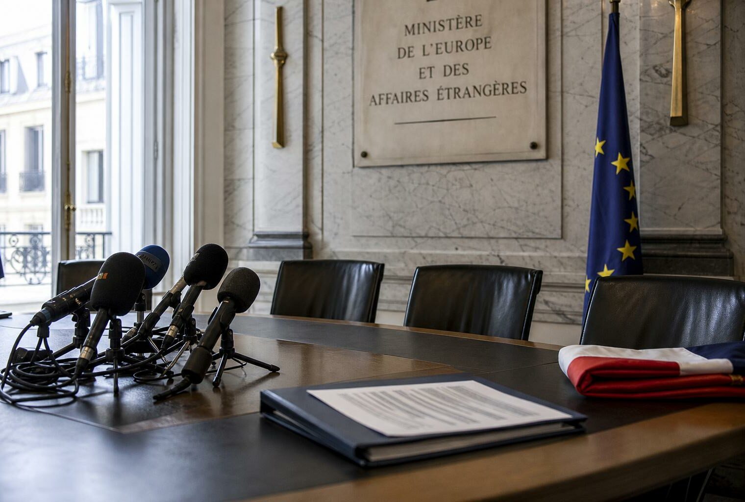 Salle de briefing diplomatique à Paris avec micros, drapeau français partiel et ambiance institutionnelle après une tension UE-Israël