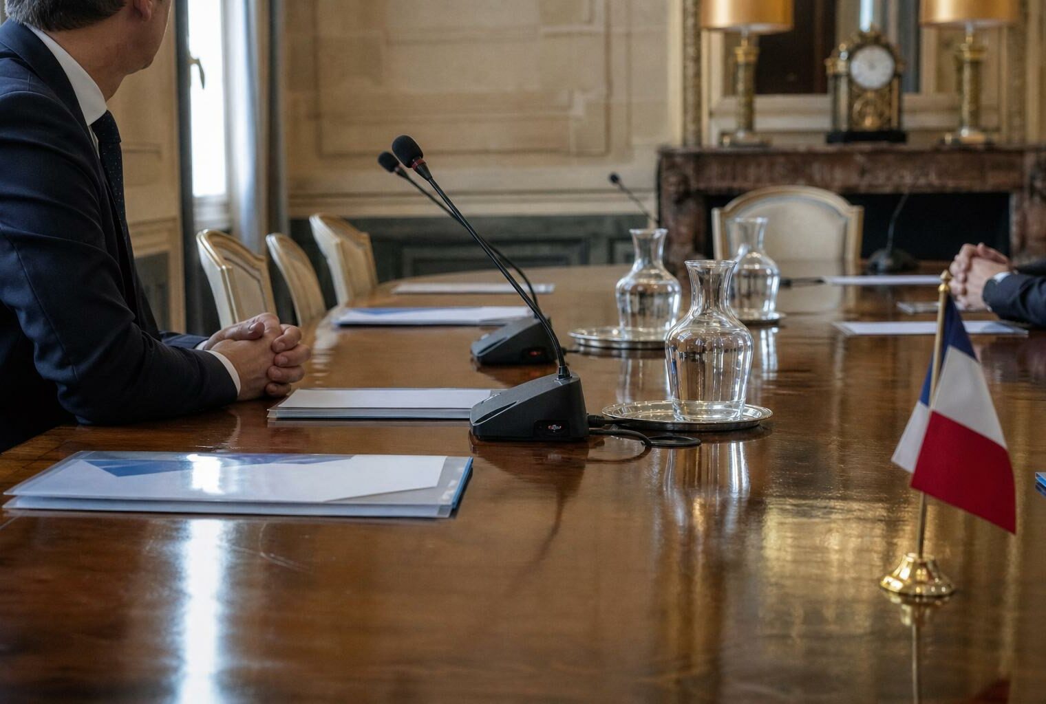Réunion diplomatique bilatérale dans un salon institutionnel français avec deux délégués anonymes et un drapeau tricolore discret.