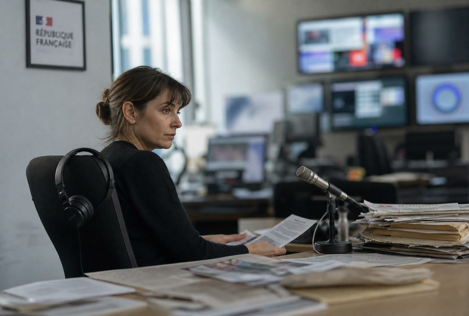 Journaliste dans une rédaction parisienne avec écrans flous et document institutionnel français en arrière-plan