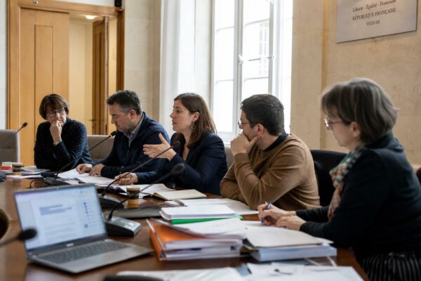 Réunion institutionnelle en France sur la protection de l’enfance, avec micros et dossiers autour d’une table.