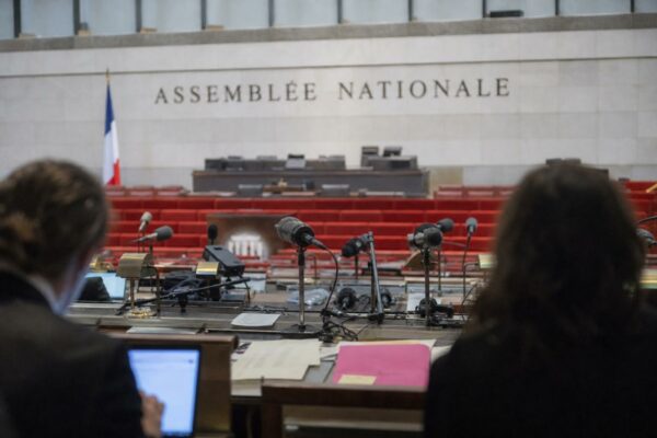 Salle de presse à l’Assemblée nationale avec micros et sièges vides, illustrant le débat sur la concentration des médias.