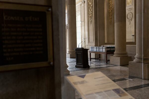 Salle vide du Conseil d’État à Paris avec marbre, colonnes et pupitre, dans une ambiance institutionnelle sobre.