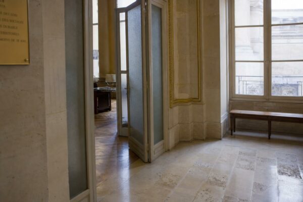 Couloir lumineux de l’Assemblée nationale, vide et institutionnel, avec marbre clair et boiseries.