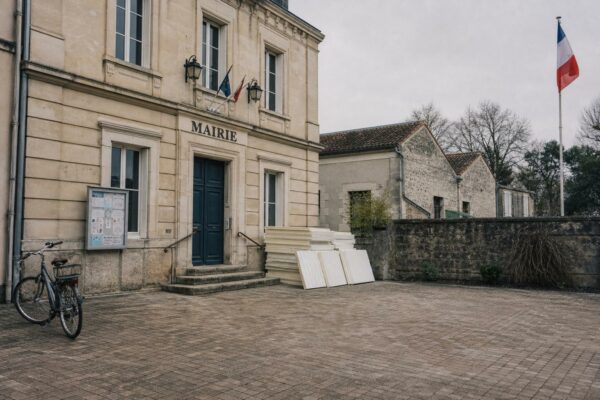 Façade d’une mairie française avec drapeau tricolore discret et cour municipale calme, illustrant le débat sur l’écologie à droite.