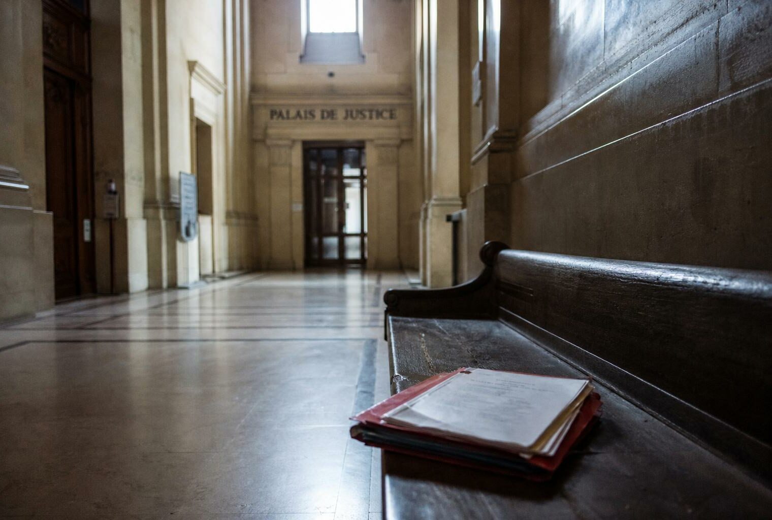 Couloir de palais de justice à Paris avec dossier juridique fermé, illustrant l’enquête judiciaire visant un candidat à la présidentielle.