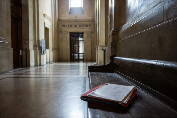 Couloir de palais de justice à Paris avec dossier juridique fermé, illustrant l’enquête judiciaire visant un candidat à la présidentielle.
