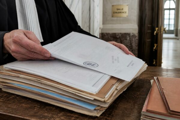 Gros plan éditorial sur un dossier judiciaire dans un tribunal français, avec tampon officiel et marbre flou en arrière-plan.