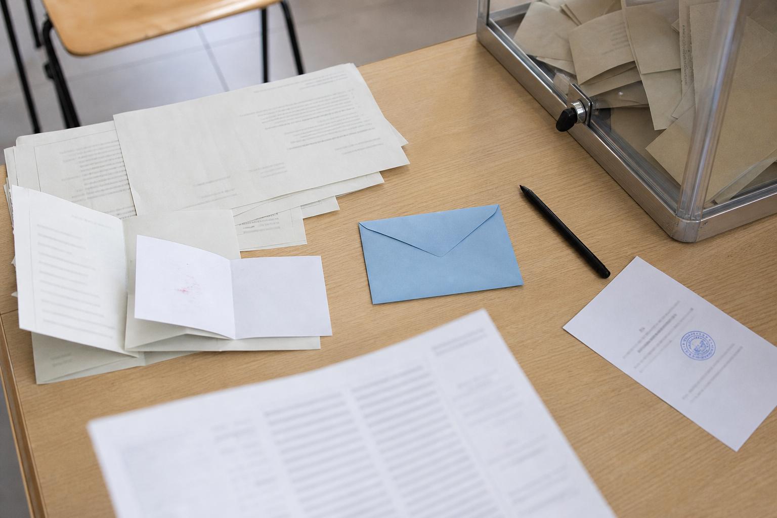 Vue en plongée d’un bureau de vote avec bulletins, enveloppe bleue et urne transparente, illustrant l’annulation d’une élection municipale.