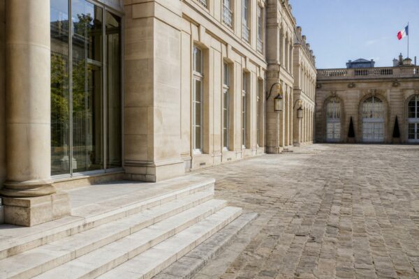 Cour de l’Élysée vide à Paris, avec lumière claire et drapeau tricolore discret en arrière-plan.