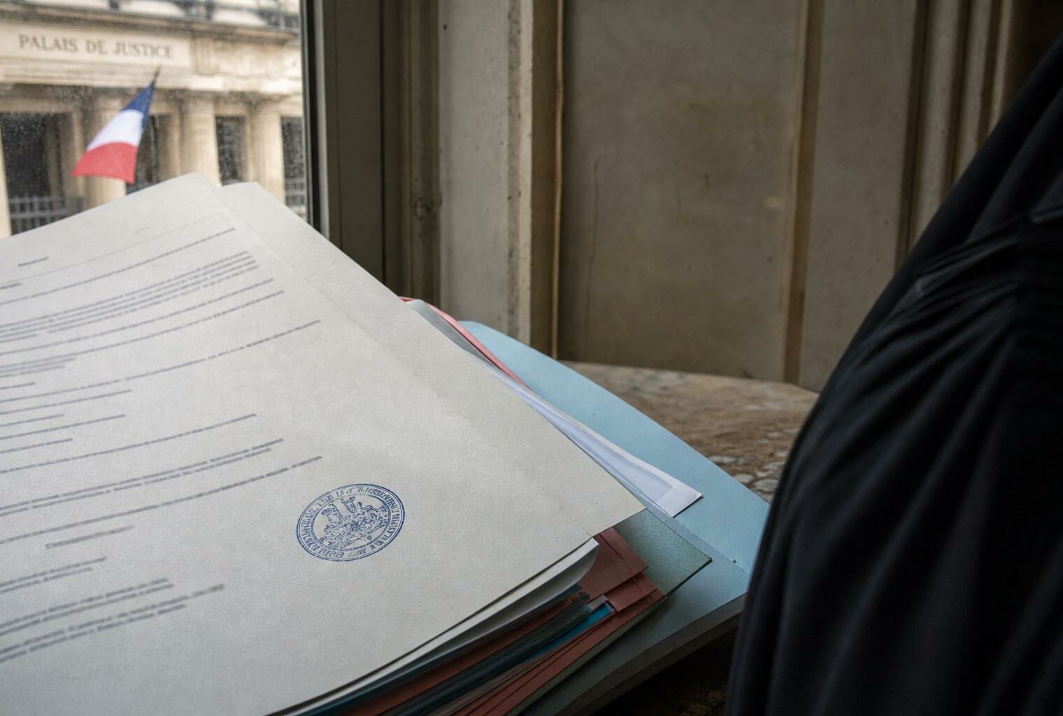 Dossier judiciaire dans un tribunal français avec tampon officiel et robe d’avocat, en photojournalisme éditorial.