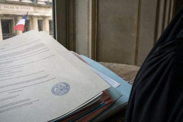 Dossier judiciaire dans un tribunal français avec tampon officiel et robe d’avocat, en photojournalisme éditorial.