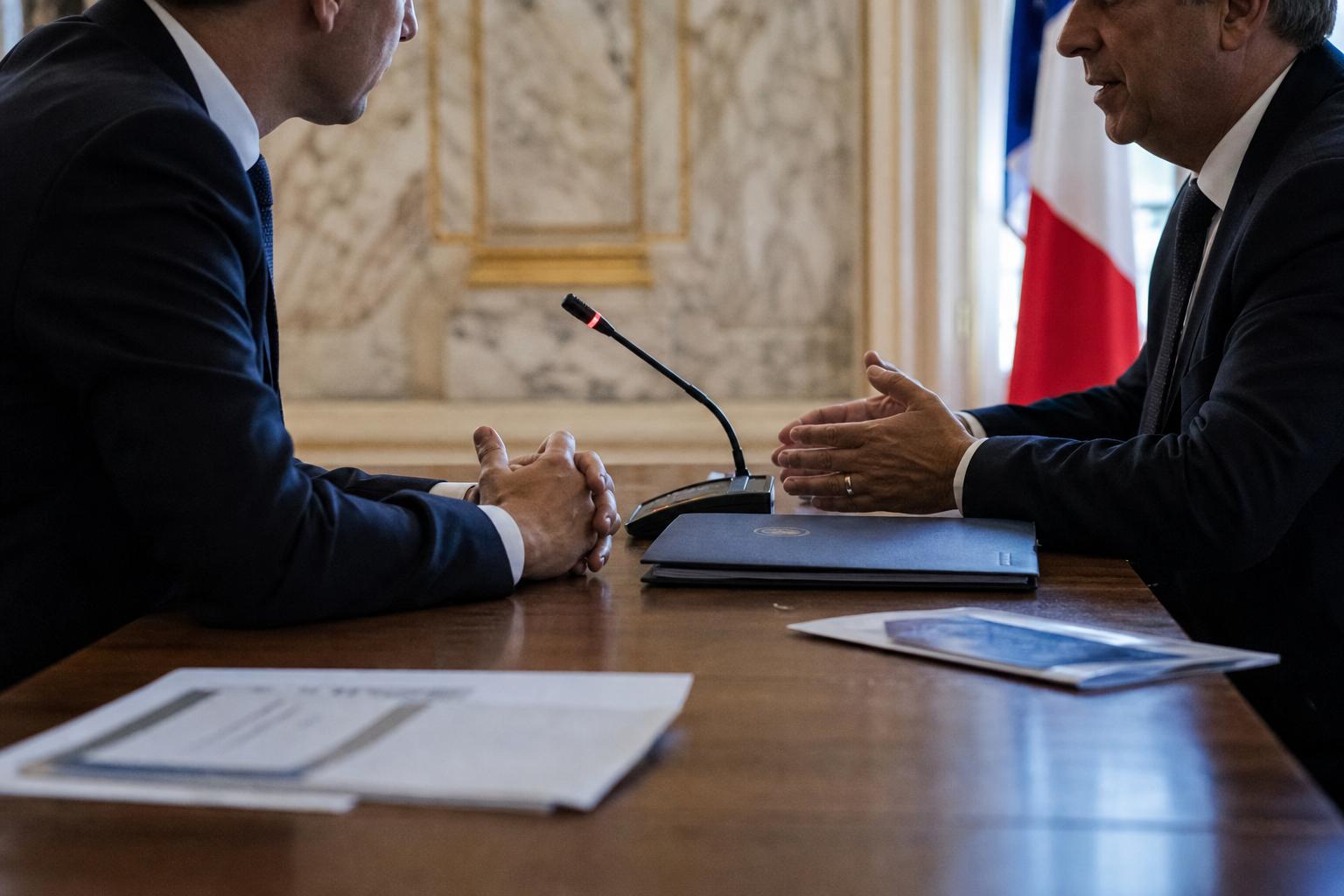 Réunion diplomatique entre deux responsables anonymes dans un ministère français, avec micro de table, dossiers et drapeau tricolore discret en arrière-plan.
