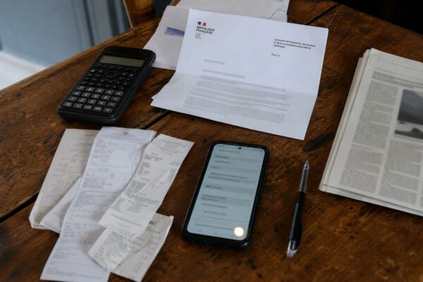 Flat lay photojournalistique d’un bureau avec reçus carburant, calculatrice et courrier administratif français pour illustrer l’aide carburant.