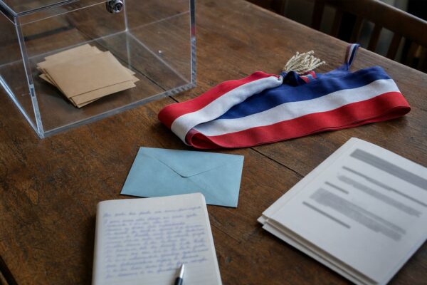 Table de campagne politique avec urne transparente et écharpe tricolore dans un contexte rural français