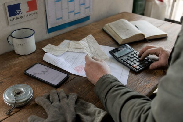 Photo de presse d’un agriculteur examinant des reçus de carburant et un devis de GNR sur une table de ferme.