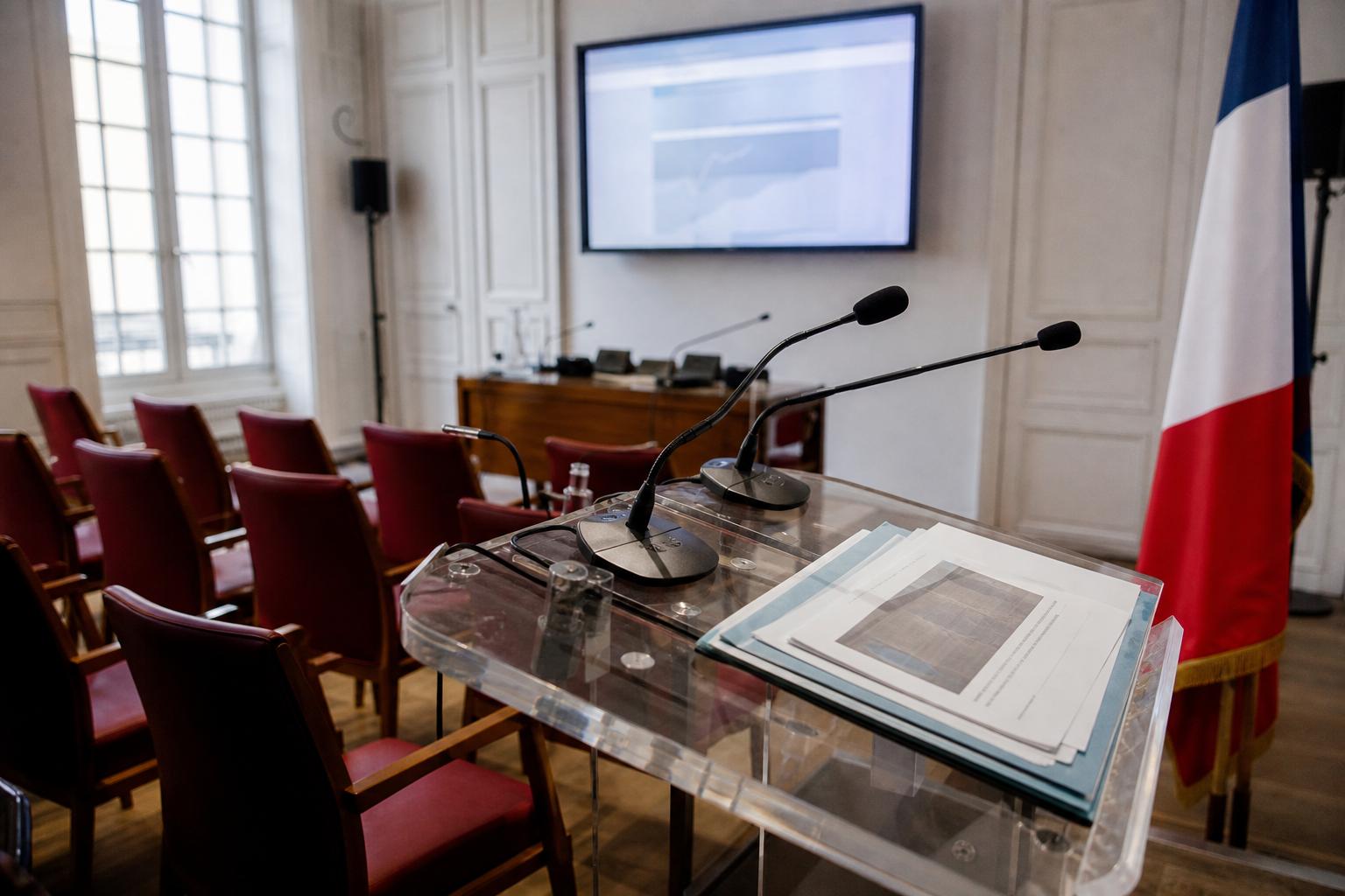 Salle de presse ministérielle française avec micros, pupitre vide et drapeau tricolore, sur fond de crise du kérosène et du transport aérien en Europe