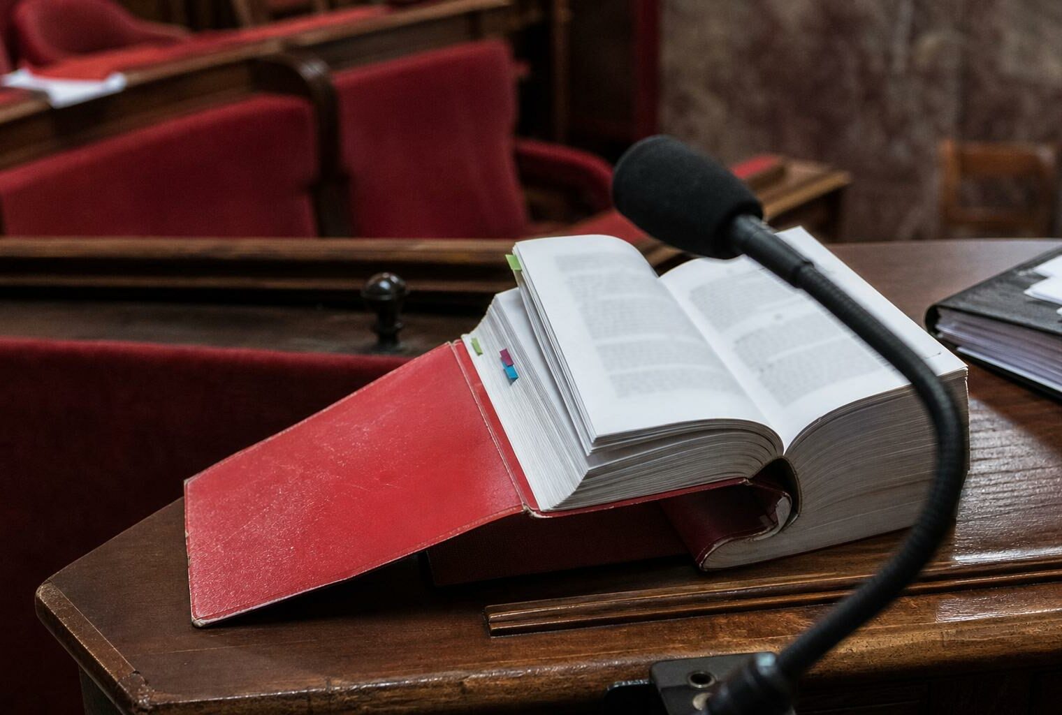 Close-up of a French legal code and parliamentary microphone in an Assembly committee room, illustrating the debate on imprescriptibility of crimes against minors.