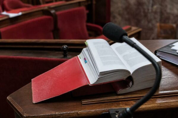 Close-up of a French legal code and parliamentary microphone in an Assembly committee room, illustrating the debate on imprescriptibility of crimes against minors.