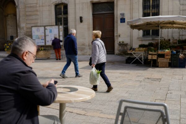 Place de petite ville française avec passants anonymes devant la mairie, en scène de reportage claire et naturelle.