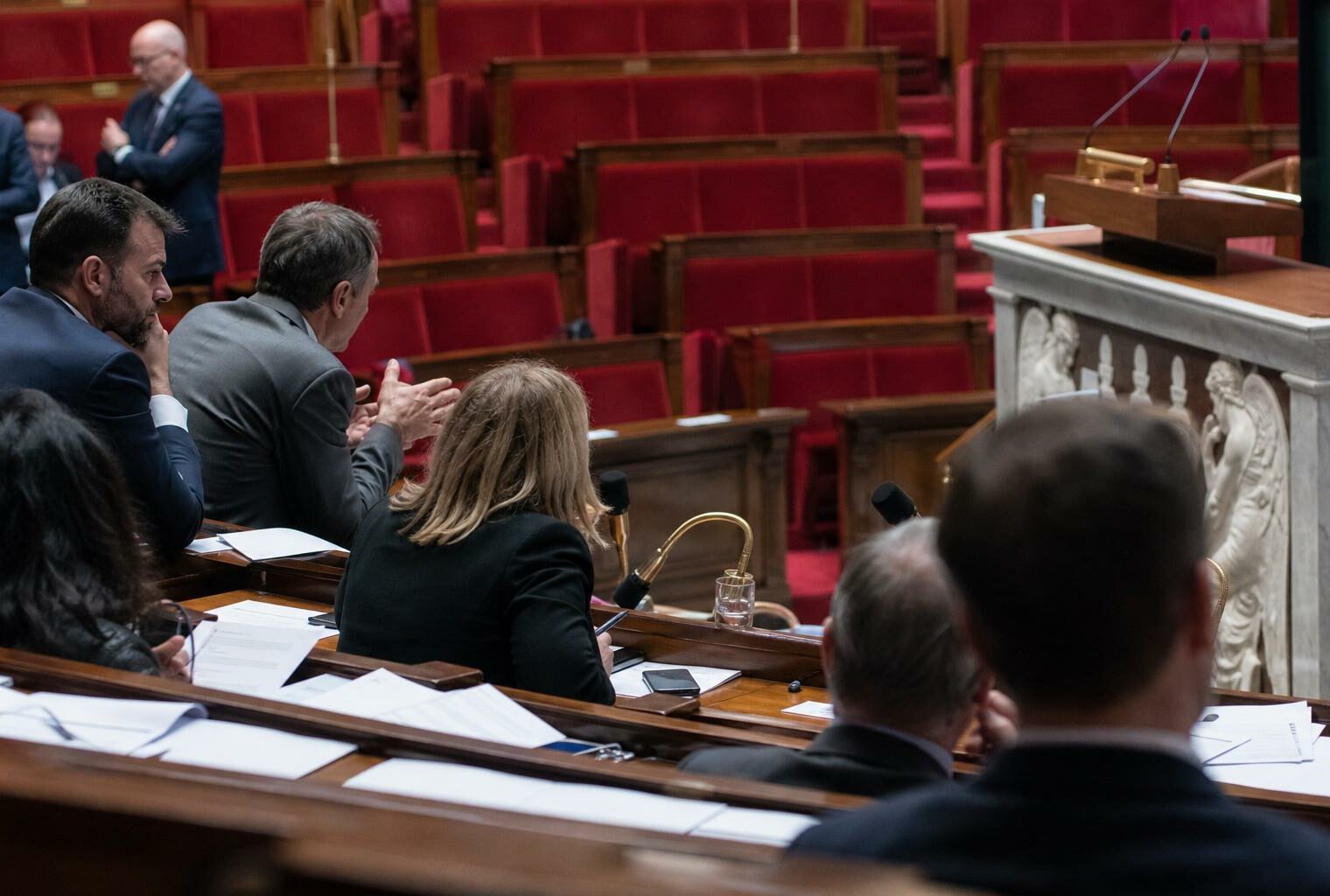 Vue oblique de l’hémicycle de l’Assemblée nationale avec sièges rouges et pupitre, pour illustrer le débat sur la loi d’urgence agricole.