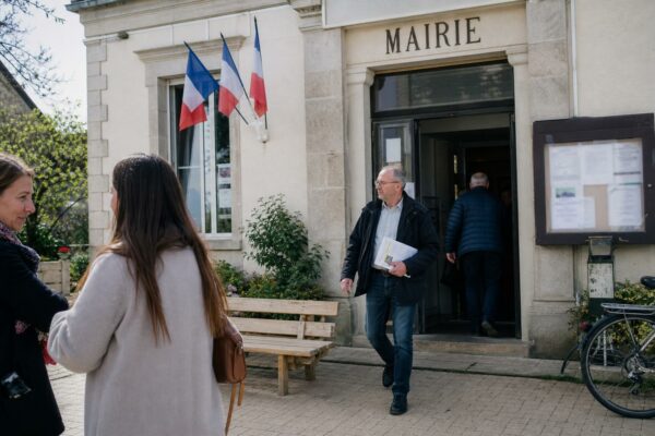 Des habitants anonymes devant une mairie de quartier, dans une scène de vie citoyenne en lumière naturelle.