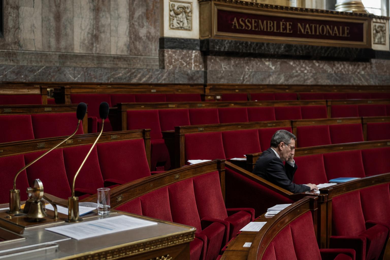 Vue documentaire de l’Assemblée nationale avec sièges rouges vides et micros, illustrant le débat politique sur le narcotrafic.