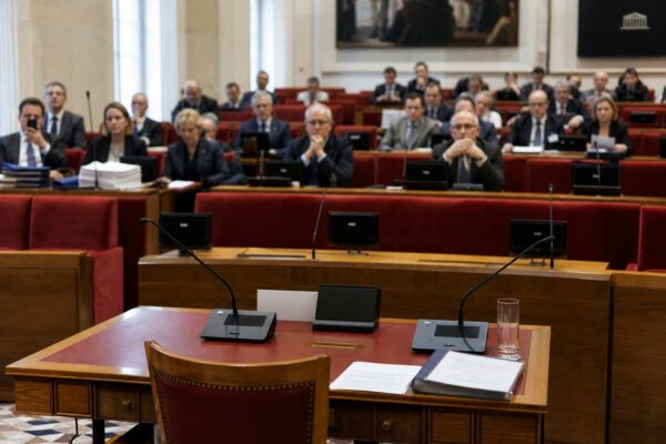 Salle d’audition parlementaire française avec micros de table, sièges rouges et ambiance institutionnelle sobre.