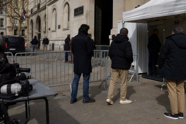 Périmètre de sécurité calme devant un bâtiment judiciaire parisien, silhouettes anonymes et barrières fermées.