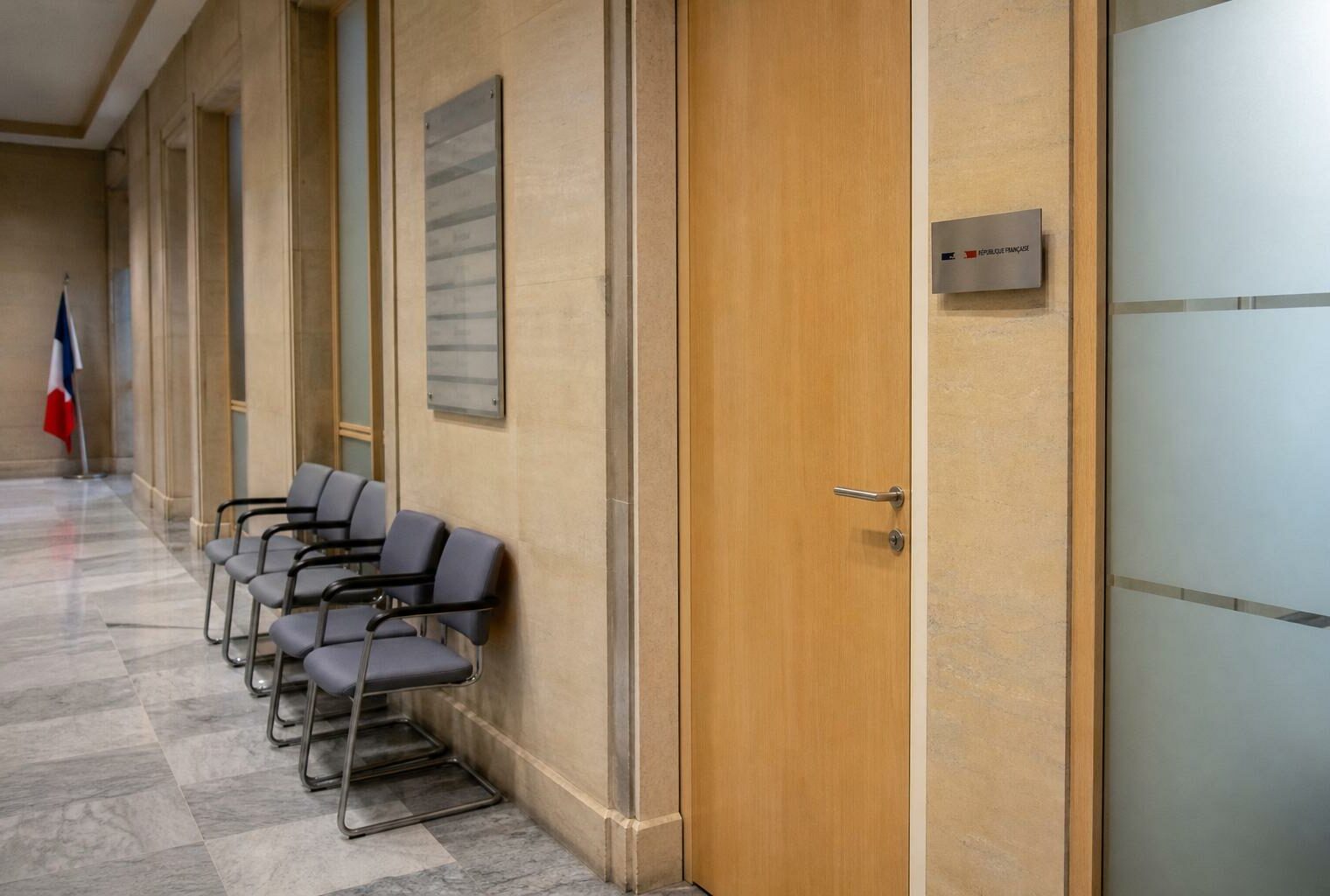 Couloir clair d’une institution française, porte close et chaises vides, ambiance sobre sur le pouvoir politique.