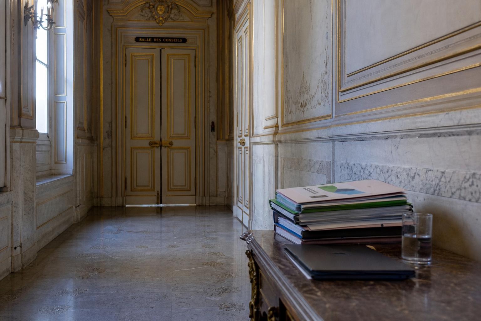 Couloir institutionnel vide à Matignon avec dossiers de préparation et ambiance de réunion sur la planification écologique