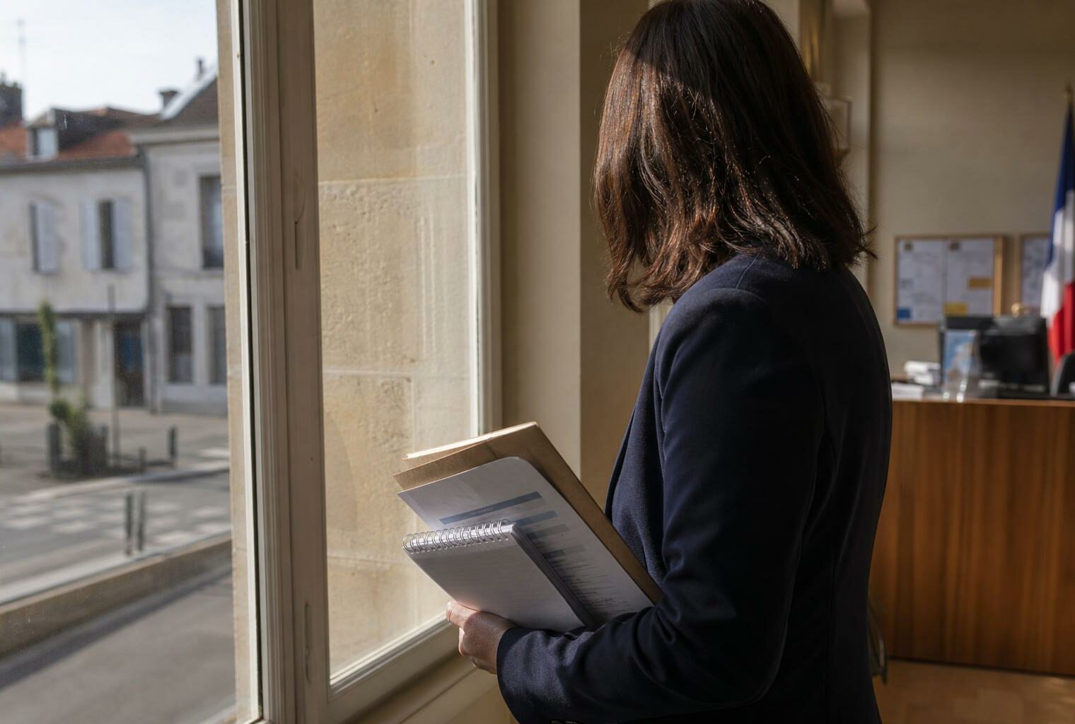 Collaborateur politique anonyme dans une mairie de province, carnet à la main, en lumière naturelle