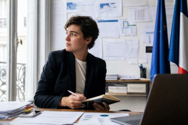 Portrait d’un stratège de campagne en bureau parisien, avec documents flous et ambiance de présidentielle.