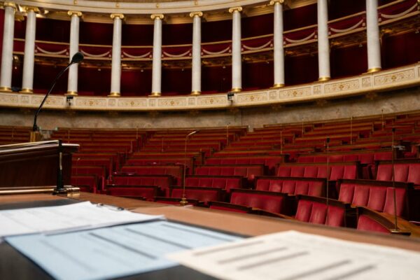 Vue large de l’hémicycle de l’Assemblée nationale avec sièges rouges vides et pupitre, illustrant le risque d’un président sans majorité.