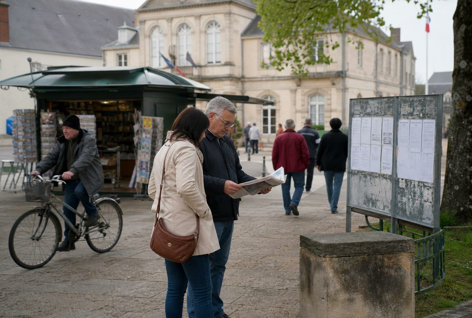 Place de mairie d’une ville moyenne française avec passants anonymes et affichettes électorales floues