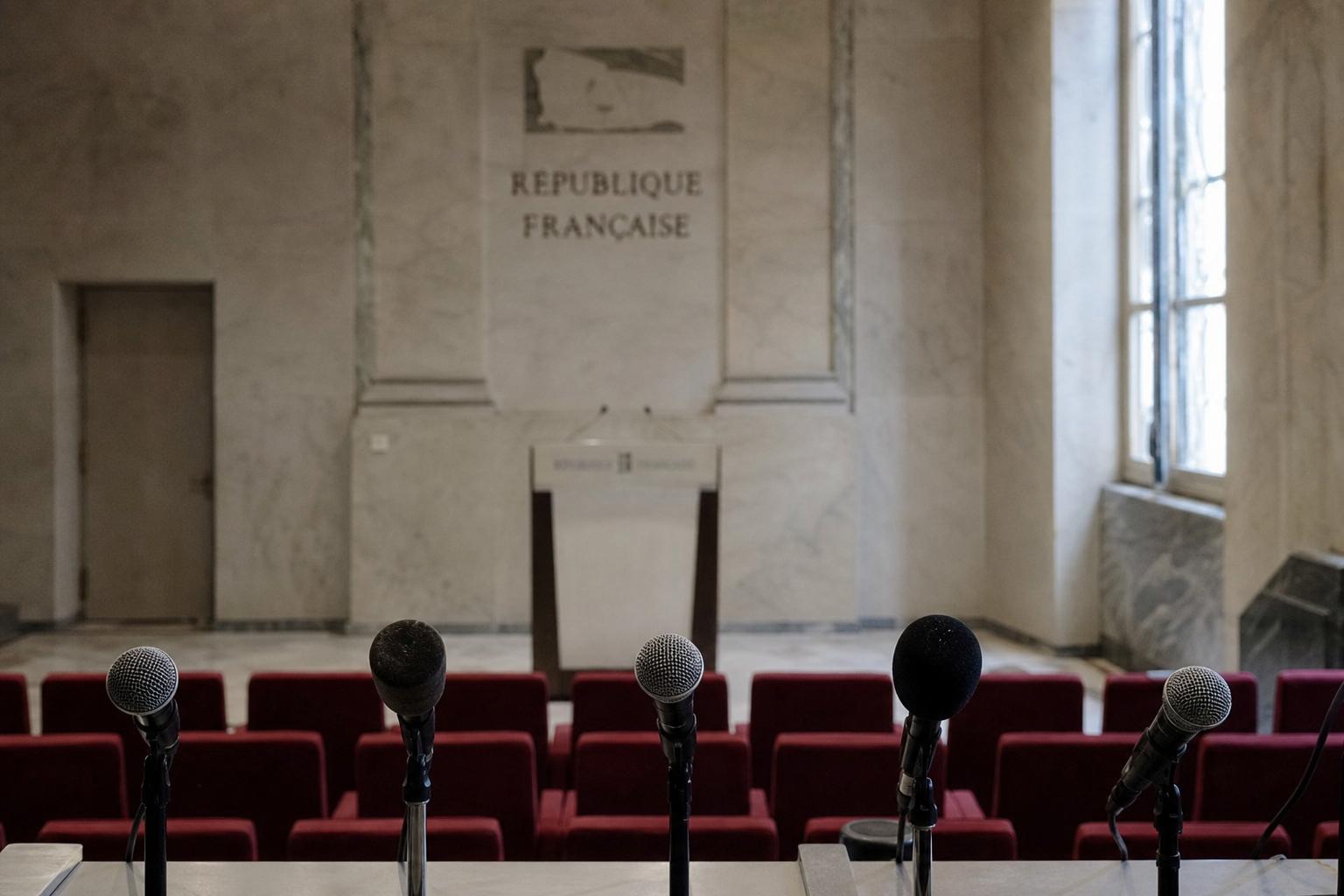 Salle de presse institutionnelle vide à Paris avec pupitre et micros, illustrant la bataille de la primaire pour 2027.