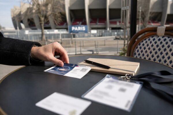 Main d’un journaliste avec billet de match et carnet de notes près du Parc des Princes