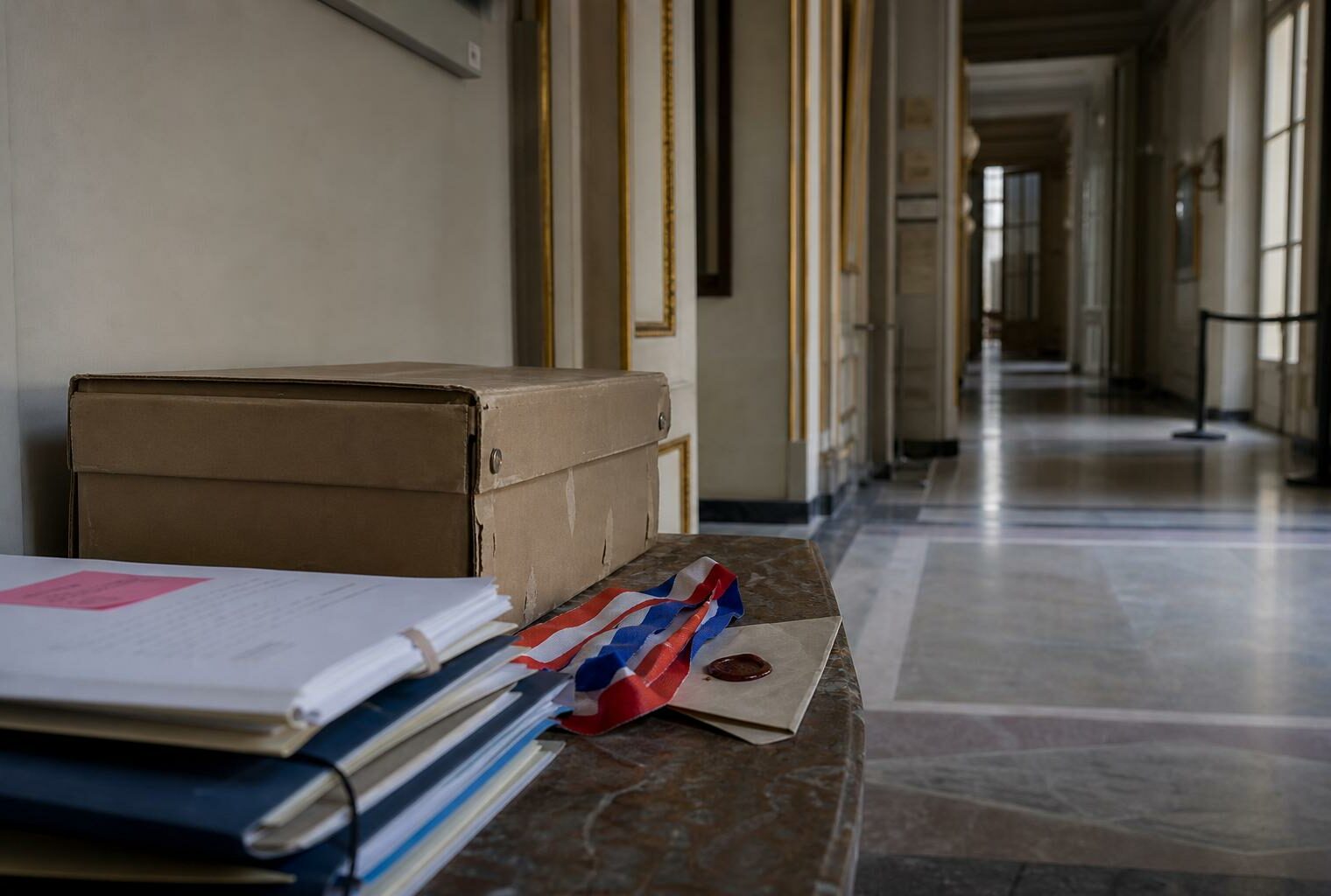 Couloir institutionnel vide au Quai d’Orsay avec dossiers officiels et enveloppe scellée, illustrant une enquête sur des cadeaux diplomatiques