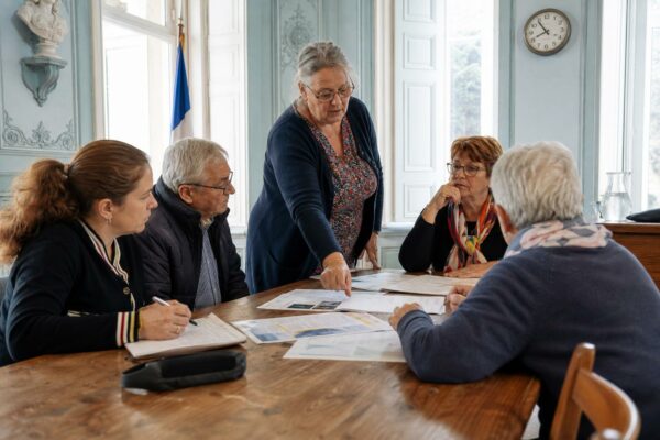 Réunion dans une mairie française autour des factures d’électricité et de la chaleur, avec cinq personnes anonymes.