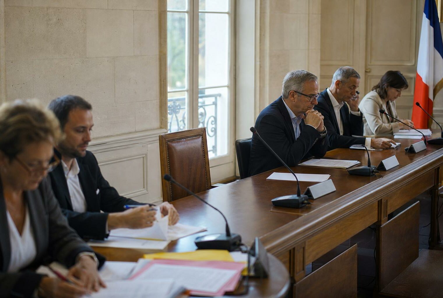 Salle municipale française avec chaise vide, micros et dossiers flous pour illustrer la protection de l’enfance.