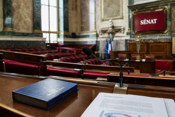 Salle de commission du Sénat avec micros et sièges rouges pour un débat sur l’enseignement supérieur privé