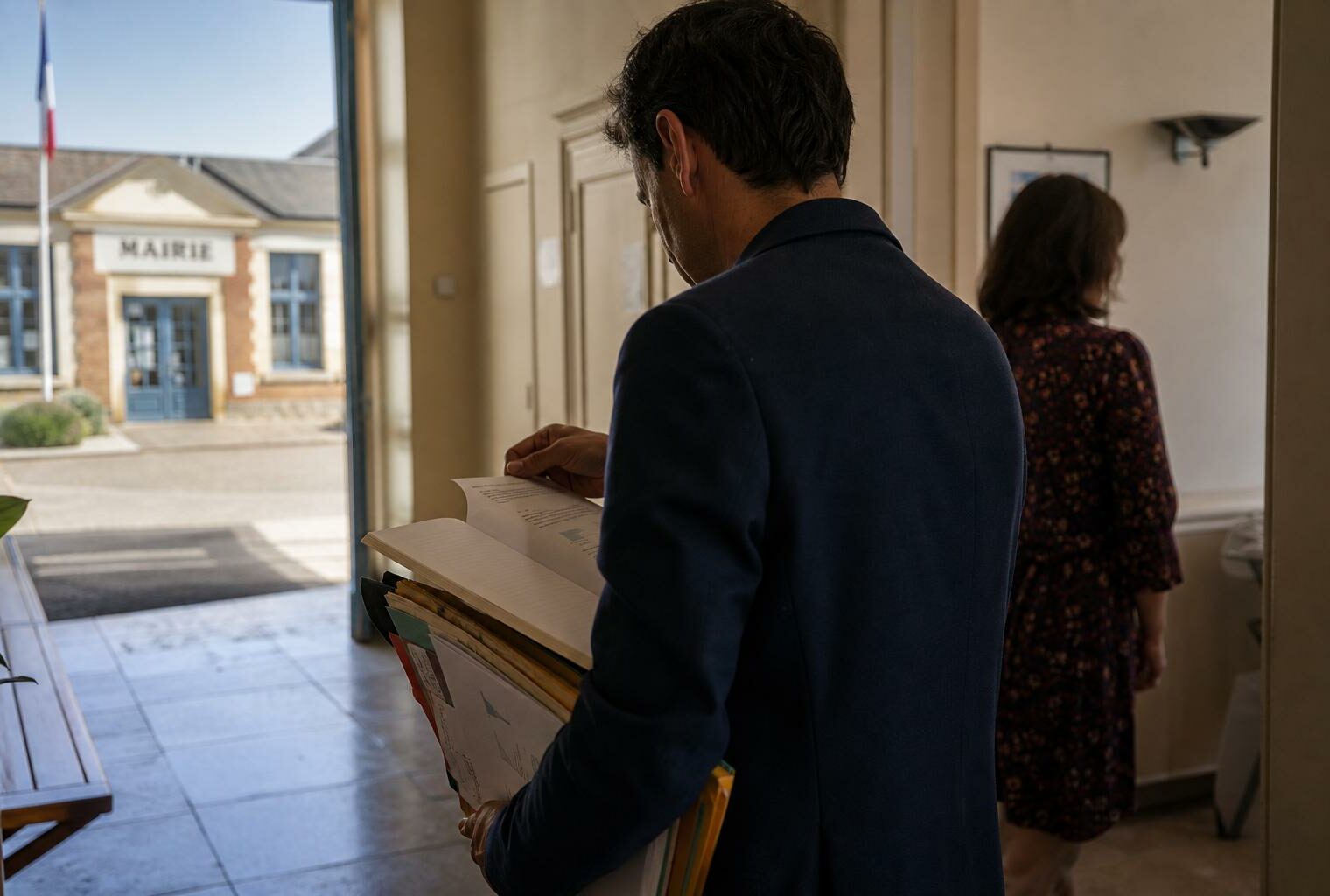 Élu local anonyme dans une mairie française, dossier à la main, en préparation des sénatoriales.