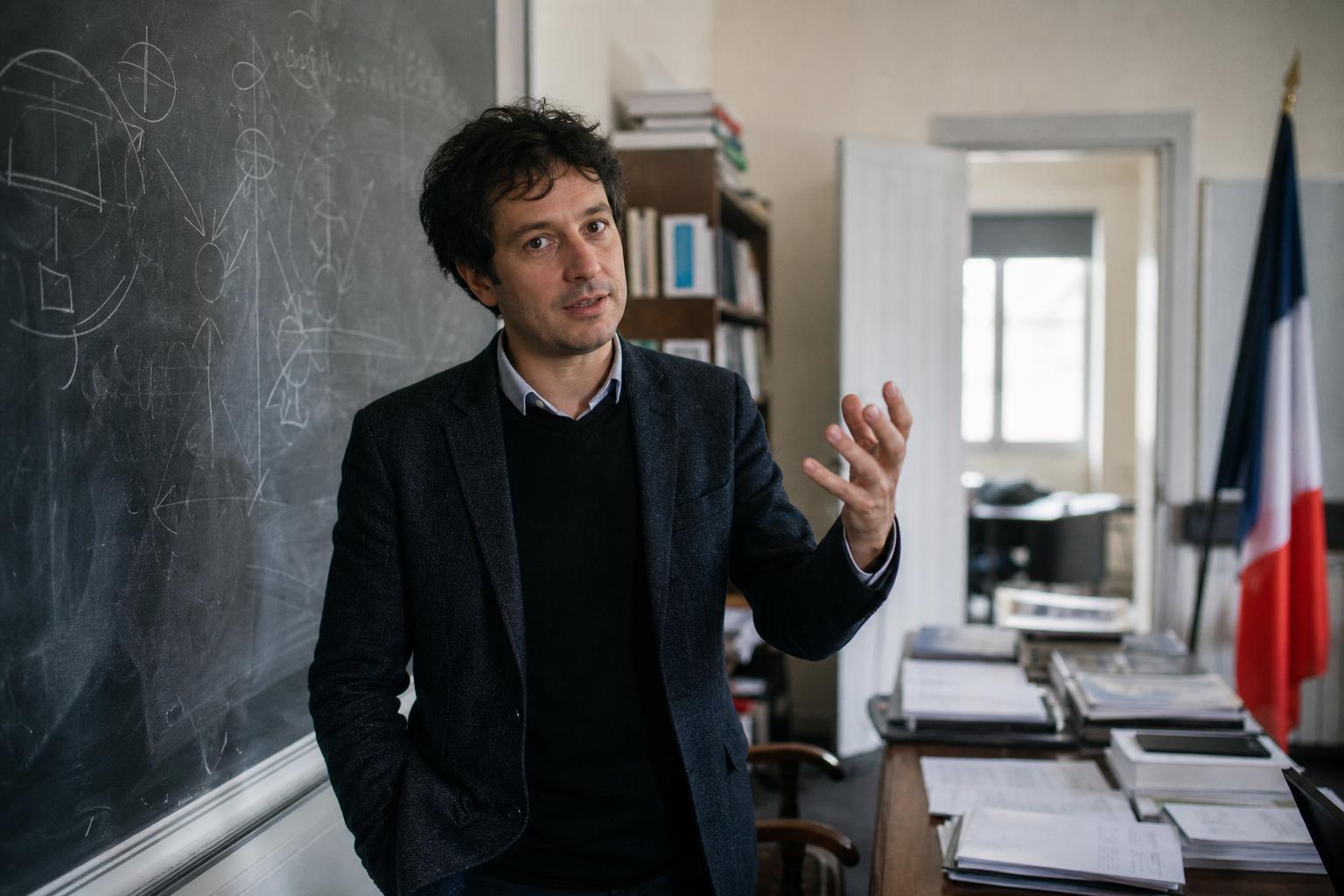 Portrait photojournalistique d’une chercheuse en sociologie devant un tableau noir dans un cadre universitaire français.