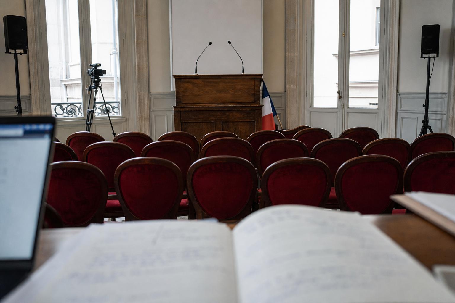 Salle de presse politique française vide avec pupitre, micros et drapeau tricolore partiel avant une annonce présidentielle.