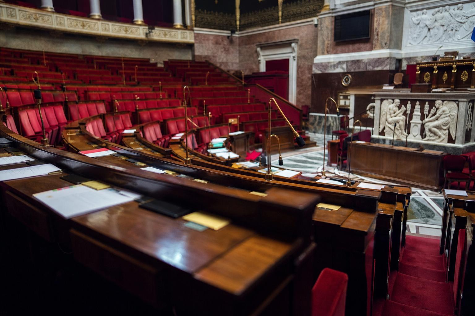 Hémicycle de l’Assemblée nationale pendant le débat sur le projet de loi d’urgence agricole, avec sièges rouges et pupitres en vue oblique